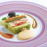 オマール海老と8種ほどの野菜を寄せたテリーヌ。トリュフとトマトのドレッシングを添え、濃厚なウニのソースでいただく。脇に添えたタラバガニのカクテルとキャビアが贅沢な逸品です。