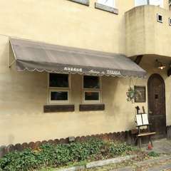 素朴な雰囲気を感じさせる、淡い色の外観と茶色い木の扉 