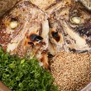 鯛のかぶとと米を、土鍋で炊いた名物料理。鯛と鰹の出汁がよく出ています。ゴマと小ネギをアクセントに。炊きあがりまで30分程かかります。鯛茶漬けもできます。（＋200円）