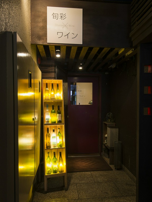 ほの暗いビルの中、ライトアップされたワインボトルがいざなう店