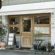 奈良・西大寺の細い街路に面し、白いオーニングに木製の扉、オリーブの鉢植えが飾られた洒落た外観。店内は木のぬくもりあふれるインテリアに心が落ち着きます。日常から離れて過ごしたい時に訪れたいお店です。
