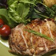 地鶏の旨みを引き立たせる調理方法で皮がパリッと中がジューシーな仕上がり。添えられている温野菜のサラダも人気メニュー。