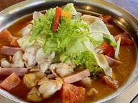 イタリア料理の手法による特製トマトソースをベースとした色彩豊かなもつ鍋です。北海道旭川産白もつ、八女産キャベツ、八女産レタス、八女産トマト、博多ナス、自家製ベーコン、熊本産パプリカを使用しています。