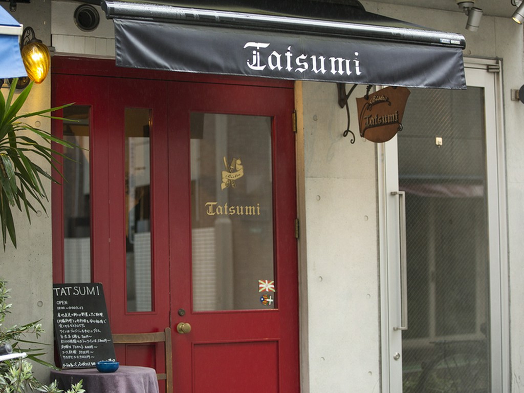 控えめな看板と赤いドアがお客さまの期待感を迎える