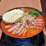 豚肉、ランチョンミート、キムチ、豆腐、野菜などが入った盛り沢山のチゲ。〆にインスタントラーメンを入れてお召し上がりください。。