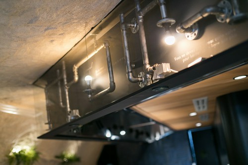 カウンター上の下がり壁にはむき出しのパイプのオブジェが