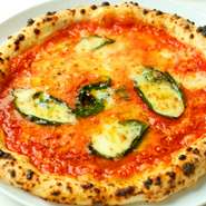 イタリアから取り寄せた薪窯で、ナポリ出身のピッザイオーロ（ピッツァ職人）が焼き上げます。トマトソース、モッツァレラチーズ、バジルのシンプルな具材が香ばしい生地によく合い、本場そのままの味を楽しめます。