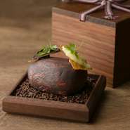 お店オリジナルの小箱状の木の器でご提供。蓋を開けると、アートのような料理が。鶏皮、鶏のレバームースの食感と旨みに、フランス・ヴァローナ社の最高級チョコレートの濃厚な香りと味わいを合わせた一品です。