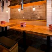 木のテーブルがぬくもりを感じさせる店内では、明るいスタッフが元気にお出迎え。赤味のある七輪のぽってりとしたフォルムと、ペンダントライトの柔らかい光が癒しを感じさせます。