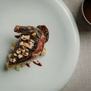 やわらかで繊細な身質を活かすために低温調理してから0℃前後で１週間寝かせた仔鳩は驚くほどしっとり滑らか。レバーを使う伝統のサルミソースの上には、さまざまな食感のナッツをのせて味わいの変化も楽しめます。