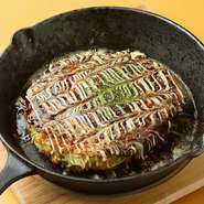 粉物は控えめに、豚肉と多めのキャベツを一気に焼き上げる【Barbe】自慢の関西風お好み焼き。隠し味に入っているレンコンの食感が特徴です。一緒に飲むなら赤ワインが料理人のおすすめです。