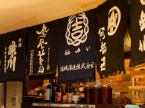 店内に飾られた前掛けは、各地の蔵元とつながっている証
