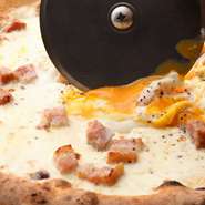 クリーミーなカルボナーラをピッツァで堪能する逸品。切る前にカッターで半熟卵を具と混ぜ合わせます。