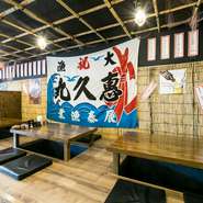 大漁旗が印象的な掘りごたつ席。この席なら、靴を脱いでゆっくりした気持ちで飲むことが出来ます。壁に貼られたメニューを見ながら、あれ食べようか、これを食べようか、と迷うのも楽しみの1つ。