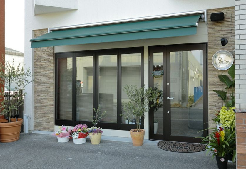 シンプルで爽やかな外観、モスグリーンのオーニングが印象的