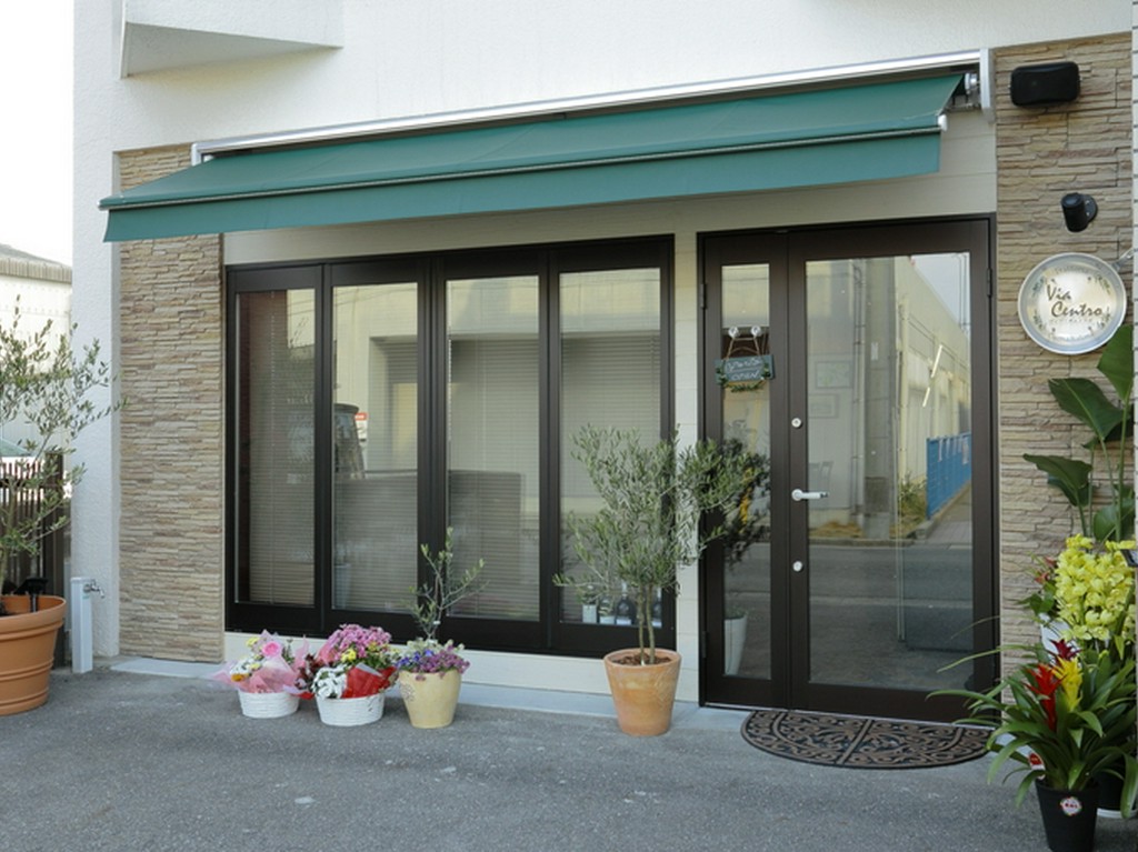 シンプルで爽やかな外観、モスグリーンのオーニングが印象的