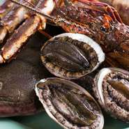 活鮑は、レアに焼き上げたときのバランスのよさが肝心。ほどほどに歯ごたえを残し柔らかさも楽しめるよう仕上げます。立ち上る磯の香りは、北海道産ならでは。真っ白で大粒の「青森県産にんにく」もおすすめです。