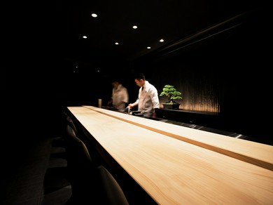 白木のカウンター席に盆栽が飾られた、シンプルでオシャレな空間