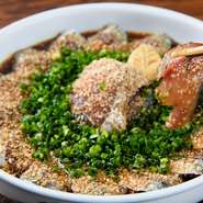 獲れたての天然生さばの上に、擦ったばかりのゴマをたっぷりとかけ、ネギを散らした一品です。盛りつけも華が咲いたような美しさ。脂ののったプリプリとした食感が楽しめます。博多名物は是非、当店で！