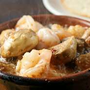 産地にこだわらず厳選された大きめの海老がたっぷりと入った具だくさんのアヒージョ。ぷりぷりとした海老の食感がたまりません。ご一緒にバケット（1個50円）はいかがですか。