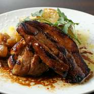 肉は200g～250gと食べ応え十分。大きな豚バラ肉をこんがりとローストした、柔らかく、よく味のしみこんだ一品です。自家製の特製ソースをかけていただきます。