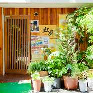 店の外観から、親しみやすさが感じられる【居酒屋　虹屋】。笑顔でお客様をおもてなしすることを心がけているため、店内にはいつでもアットホームな雰囲気です。仕事帰りにリピートして訪れる人も多数。