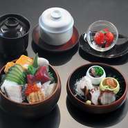 旬の素材を華やかに盛り込んだ宝石箱のような逸品。上段にはお料理、下段にはマグロ、穴子、イクラなど、季節の海の幸がご飯の上に敷き詰められています。茶碗蒸し、汁物、甘味が付いて内容盛りだくさん。