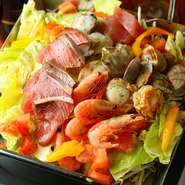 お客様のテーブルに鉄板を置いて、魚介やお野菜を和気あいあいと各自で焼いて味わっていただけるお料理です。築地でシェフが直接目利きして仕入れた新鮮な魚介類や旬の野菜をお楽しみください。