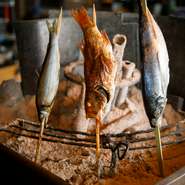 舞阪漁港や北部市場から直送される新鮮な魚を炭火で香ばしく焼き上げた一品。金目鯛やサバ、真鯛などの魚を串に刺し、豪快に焼かれます。炭の輻射熱を使用して焼くため、表面はカリッと、中はふっくら。