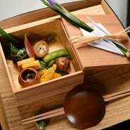 12品前後のコースのなかでもひときわ華やかな皐月のお八寸は、名残の鯛の子、アイナメの新子、的射穴子などが彩りよく盛り込まれています。白木の箱膳はオリジナルで製作。（写真は5月の献立の一例です）