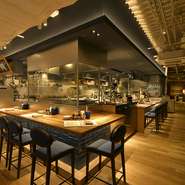 ナチュラルな木の質感と天井の鉄骨が違和感なく調和する店内。広々とした空間は開放感にあふれ、細部にまでこだわった内装が目を引きます。カウンター席では、熟成肉を丁寧に切り分ける料理人の技が見られます。