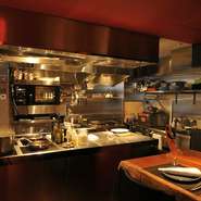 店内は、社長と社長の知り合いのデザイナーが手掛けたスタイリッシュで高級感あふれるデザイン。テーブルが見渡せるオープンキッチン、その奥には厚みのある板のカウンターがあります。