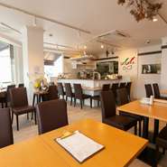 オーナーシェフのチャームポイント、メガネをデザインしたシンボルマークがアクセントカラーとして使用。壁一面の大きなガラス窓は開放的で、店内は明るく洗練されています。