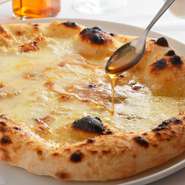 長年の経験を積んだ自慢のピッツァ生地に、イタリア直輸入のチーズから4種類をトッピング。自家製のホットハニー（唐辛子入りのはちみつ）をかけてどうぞ。生地の食感といろいろなチーズの味わいをご堪能ください。