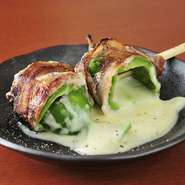 豚バラで巻いた特殊な串もの。ピーマンの中にチーズが入った豚巻きです。アツアツのとろけるチーズとピーマンのシャキシャキした食感が絶妙のハーモニーを奏でる、お店イチオシの一品。