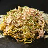 お好み焼きの上に太麺のソバと半熟卵がのせられたモダン焼き。ピリッとした辛さがくせになる味わいです。もちもちの麺とふわふわの生地がソースと絶妙に絡み合います。