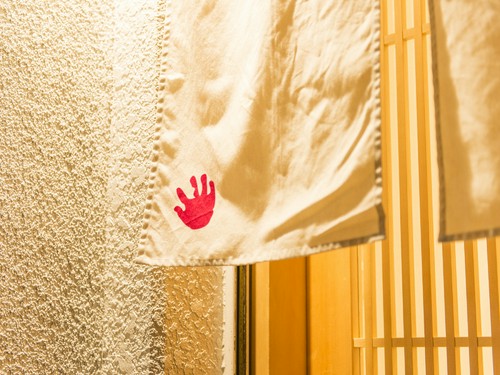息子さんの手形がデザインされた白い暖簾が目印