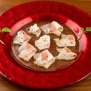 イタリアのトスカーナ地方で取れる白い大理石で、2か月半塩漬けした豚の首肉の生ハムです。熟成された脂身は舌の上で溶けるほど良質。かむ程に旨味があふれ出し、思わず唸る逸品です。