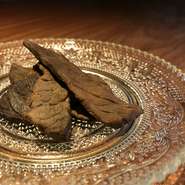 牛もも肉をオリジナルの漬けダレに一晩浸し、低温のオーブンで多少水分が残るぐらいに乾燥させています。最後にブレンドされたスモークチップで燻製した柔らかい自家製ビーフジャーキーです。