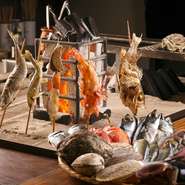 炭火を使い、離したり、近づけたりして加減しながら焼き上げる「原始焼き」。日本古来の伝統的な炭火焼をカウンター前の専用囲炉裏で行い、魚の本当の美味しさを伝えています。山形の地場野菜も「原始焼き」で提供。