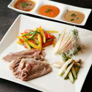 霜降りが美しく、肉質がやわらかい“三角バラ”を、つけあわせの野菜に巻いて食べていただきます。トマトソース、柚子ポン酢、ごまだれ、3種類の特製たれは、自信作ですので、それぞれたっぷりお楽しみください。