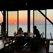 テラス席の海側は一面の窓。目の前に広がる瀬戸内海の景色はため息が出るほどの絶景が広がる。ランチは深く青い海、ディナーは夕日百選に選ばれる美しいサンセットで心まで満たされること間違いなし！