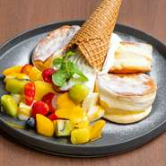 ふわしゅわ食感のパンケーキとたっぷりフルーツ、そして真ん中に豪快にトッピングされたクレミアソフトが迫力満点のフルーツパンケーキ。