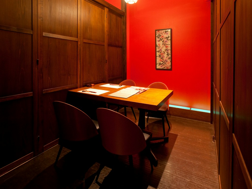 ビビッドな朱色の壁と幻想的なライティングで映える個室