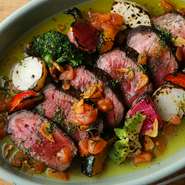 赤身の牛肉を豪快に炭焼きステーキにした贅沢な一皿。オリーブオイル、にんにく、ビネガー、ローズマリーを使ったソースはさっぱりとした味わいで、牛肉と好相性です。