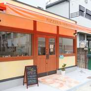 お店は閑静な住宅街に位置し、周辺は昼も夜も静か。やさしい明かりが灯る店内は開放的で、落ち着いて食事ができます。大きな窓からは石窯とその中で上がる炎が覗けます。
