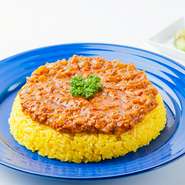 たっぷり入った国産挽肉の美味しさを、スパイシーなカレーで存分に味わえる一皿。目の覚めるような青色の皿に、黄色のターメリックライスと茶色のキーマカレー、あしらいのパセリの緑が映え、食欲を一層そそります。