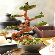 器以外はすべてスイーツ! 　土台はバニラ・黒ゴマ・抹茶のアイスがつまり、その上にワラビ餅・ココア・抹茶をあしらって土のように。松の枝はパイ生地、葉は抹茶ペースト。パイをアイスにつけて食べるのがおすすめ。