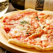 ピザの生地は、お店で手づくりされる薄めの生地「クリスピー」、使っているモッツアレラチーズはイタリア産のもの。フレッシュバジル、トマトをのせた定番ピッツァです。Mサイズ880円もあります。