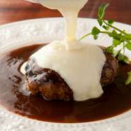 ふわふわ柔らかハンバーグにデミグラスソースをかけた状態でサーブされ、目の前でジャガイモとチーズをとろとろに煮込んだアリゴソースをかけて仕上げます。3つの味が最高のバランスの看板メニューです。